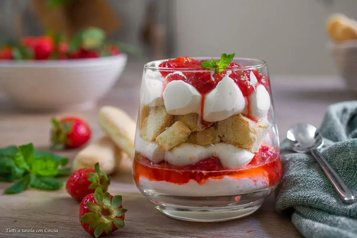 Delizioso tiramis&ugrave; alle fragole in un bicchiere, con strati di crema, savoiardi e fragole fresche.
