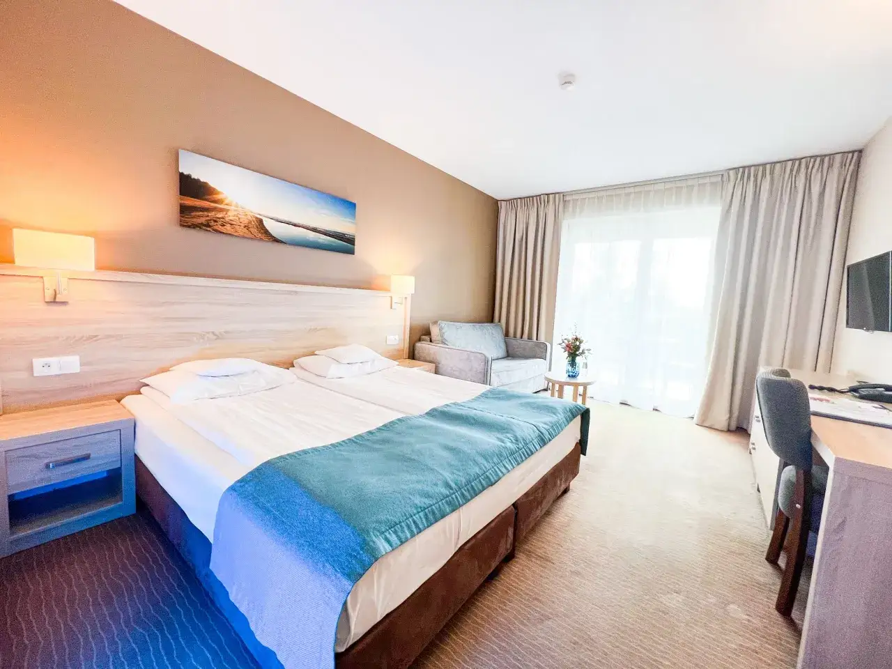 Przytulny pokój w hotelu Tristan Kąty Rybackie z dwoma łóżkami, kanapą i widokiem na morze.