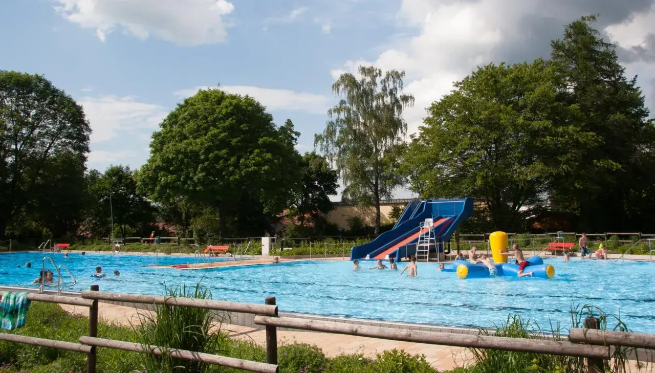 Sommerlicher Badespaß im Freibad Lahde mit Rutsche und aufblasbarem Spielzeug. Kinder planschen und genießen die Sonne.