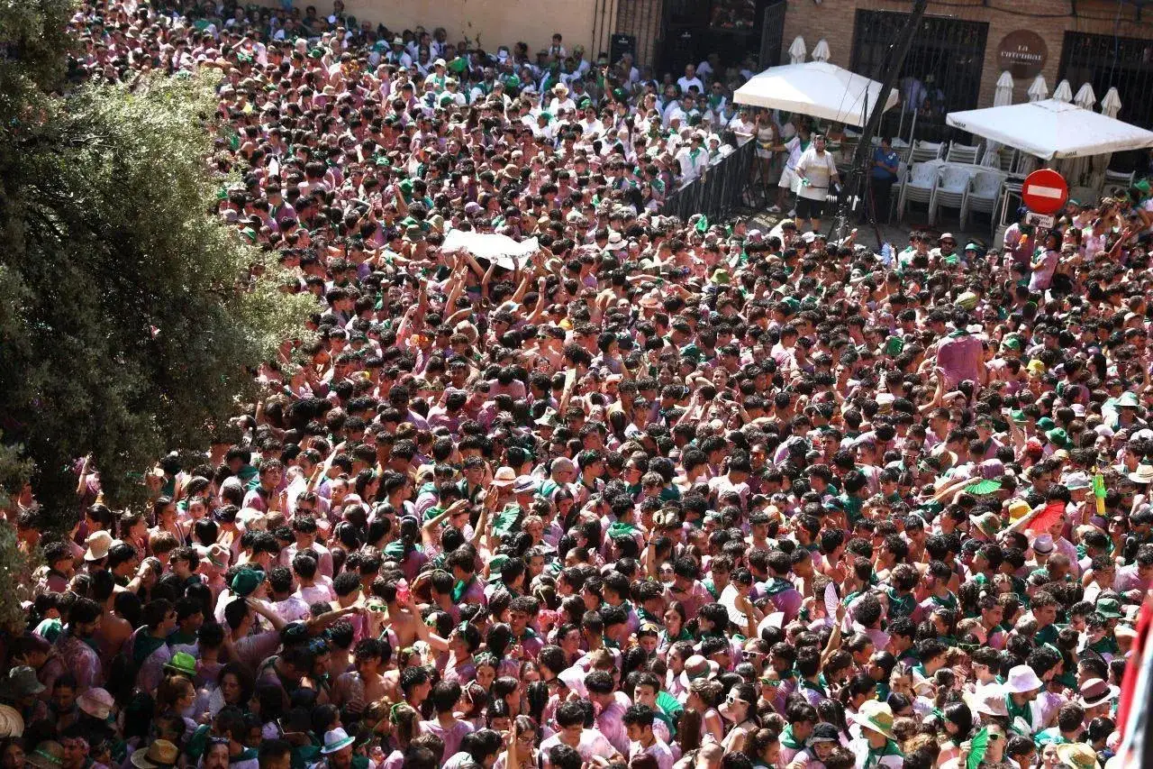 Multitud celebrando el programa fiestas Huesca. Gente con pañuelos verdes y morados, algunos levantan un objeto blanco.