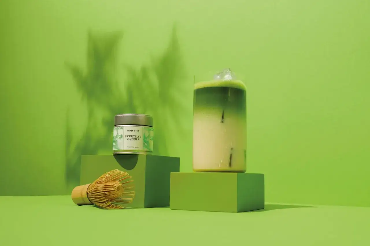 Orzeźwiający iced matcha latte z kostkami lodu, obok puszka 