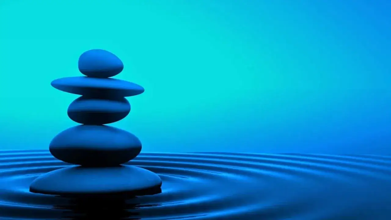 Kamienie ułożone w stos na wodzie. To wizualizacja tego, czym jest mindfulness: spokój i równowaga.