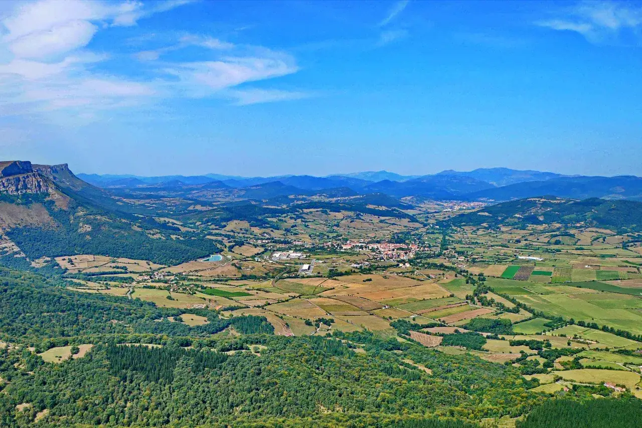 Blick &uuml;ber ein gr&uuml;nes Tal mit Feldern und einem Dorf, das an den Salto del Nervi&oacute;n erinnert.