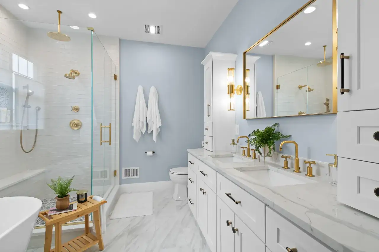 A modern bathroom with a glass-enclosed shower, dual vessel sinks with gold fixtures, and a freestanding tub.