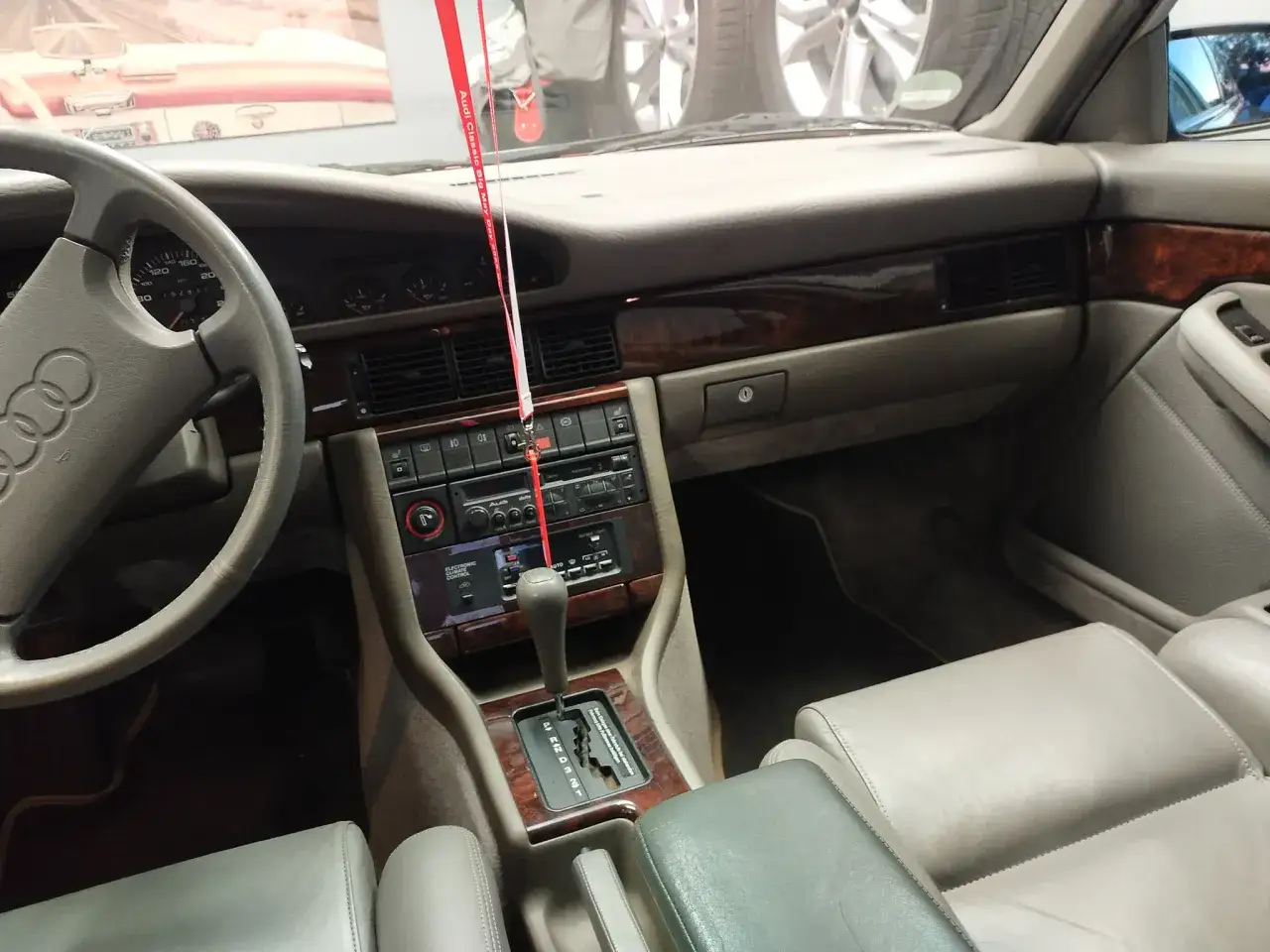 Wnętrze Audi V8 z drewnianymi wstawkami, szarą tapicerką i automatyczną skrzynią biegów.