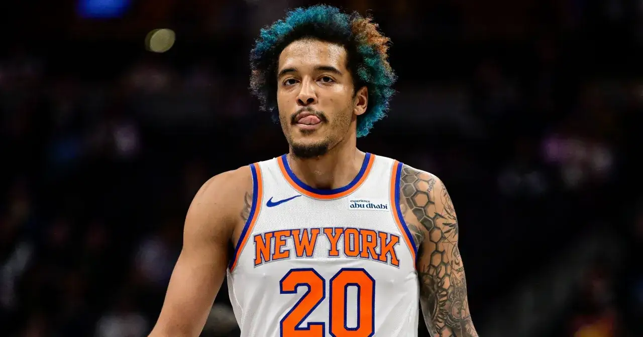 Polak w NBA, gracz New York Knicks z numerem 20, z niebieskimi włosami i tatuażami na ramieniu, pokazuje język.