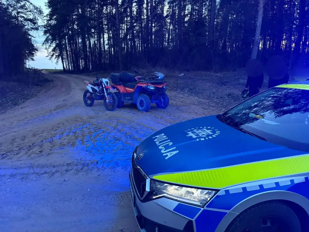 Policyjny radiowóz z niebieskimi światłami na leśnej drodze. Obok motocykl i quad. Akcja kategoria b1.