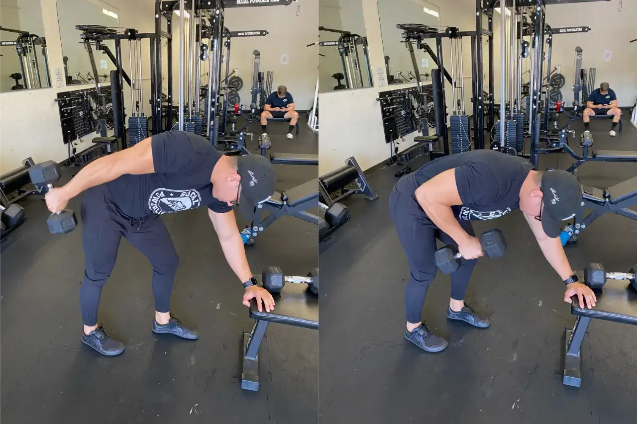 Man utför triceps med hantlar i ett gym. Han lutar sig framåt, med ena handen på en bänk för stöd, och lyfter en hantel med den andra armen.
