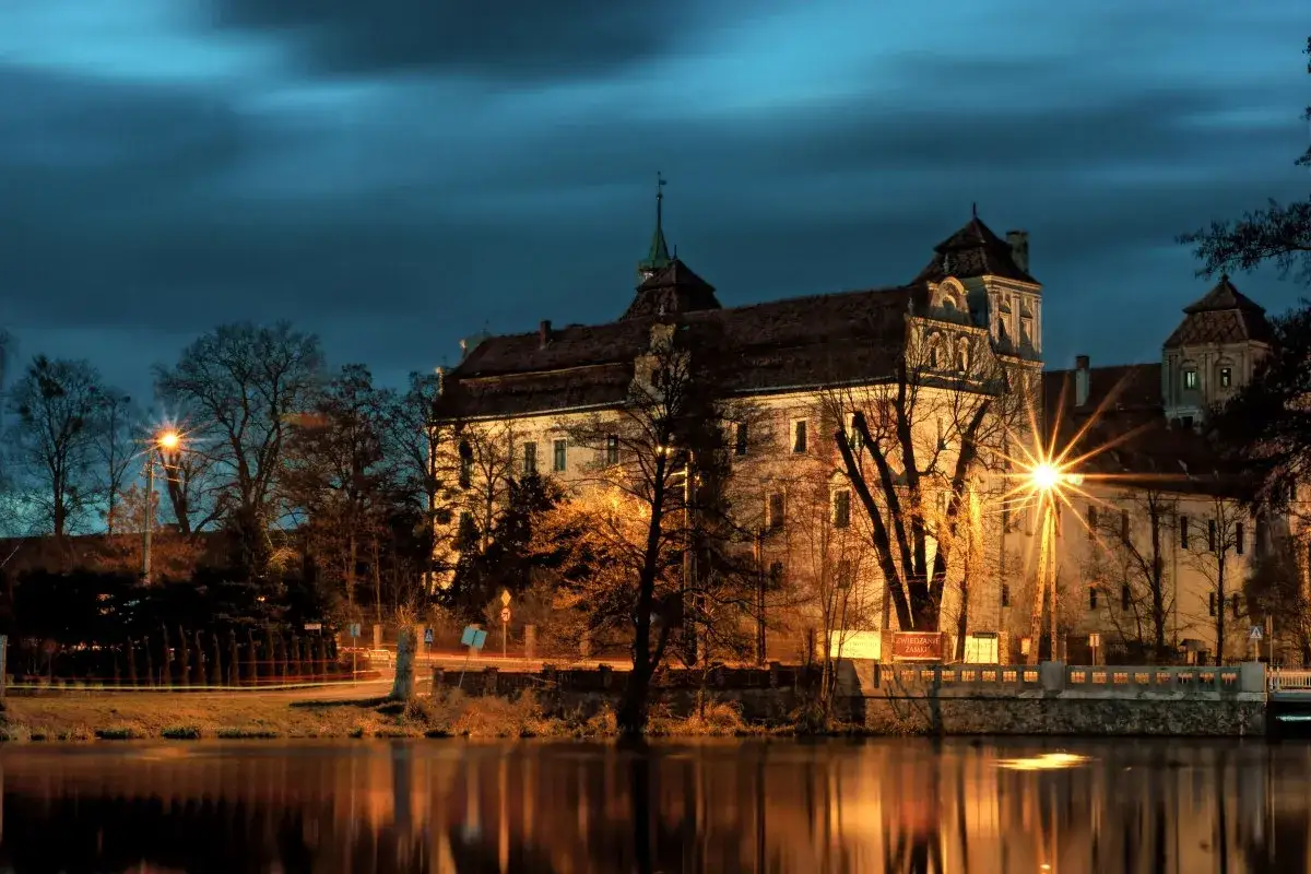 Zamek w Nysie nocą, oświetlony blaskiem latarni, to jedna z opolskie atrakcje. Jego odbicie w wodzie tworzy magiczny widok.