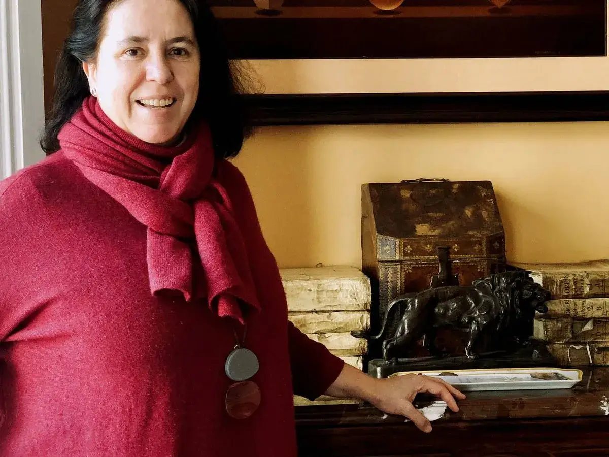 Una mujer sonr&iacute;e junto a una escultura de le&oacute;n y objetos antiguos, quiz&aacute;s en un palacio de Loyola.