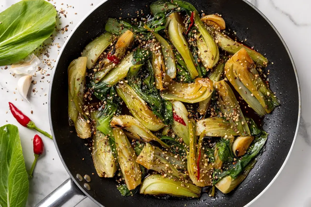 Verdure in padella, bok choy saltato con aglio, peperoncino e semi di sesamo, un piatto saporito e colorato.