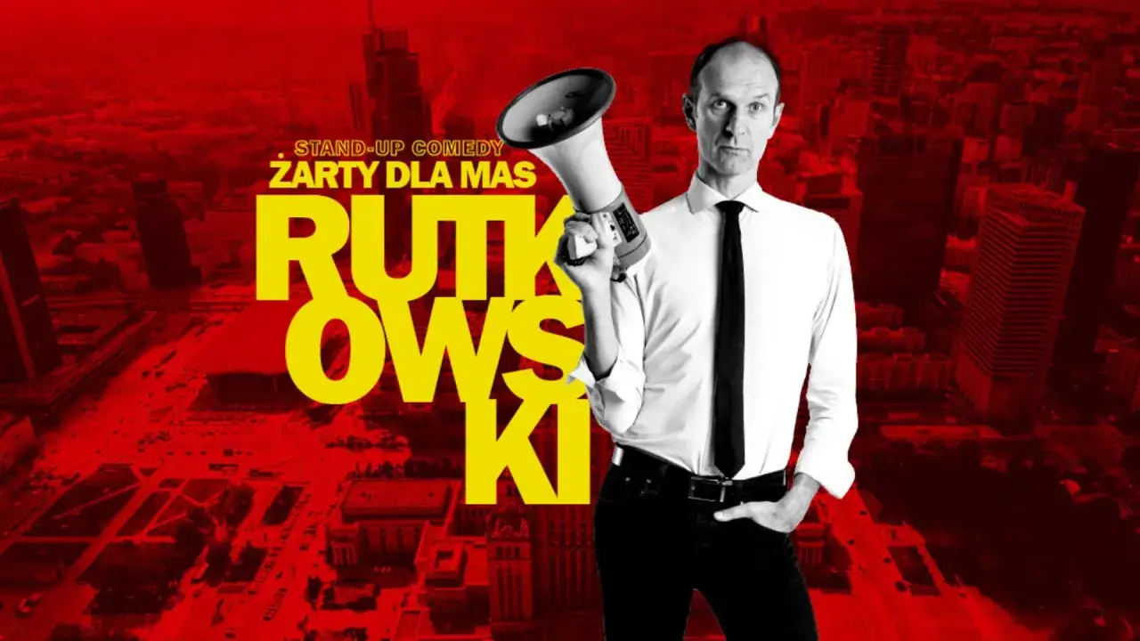 Rutkowski stand-up comedy. Mężczyzna w białej koszuli i krawacie trzyma megafon na tle czerwonego miasta.