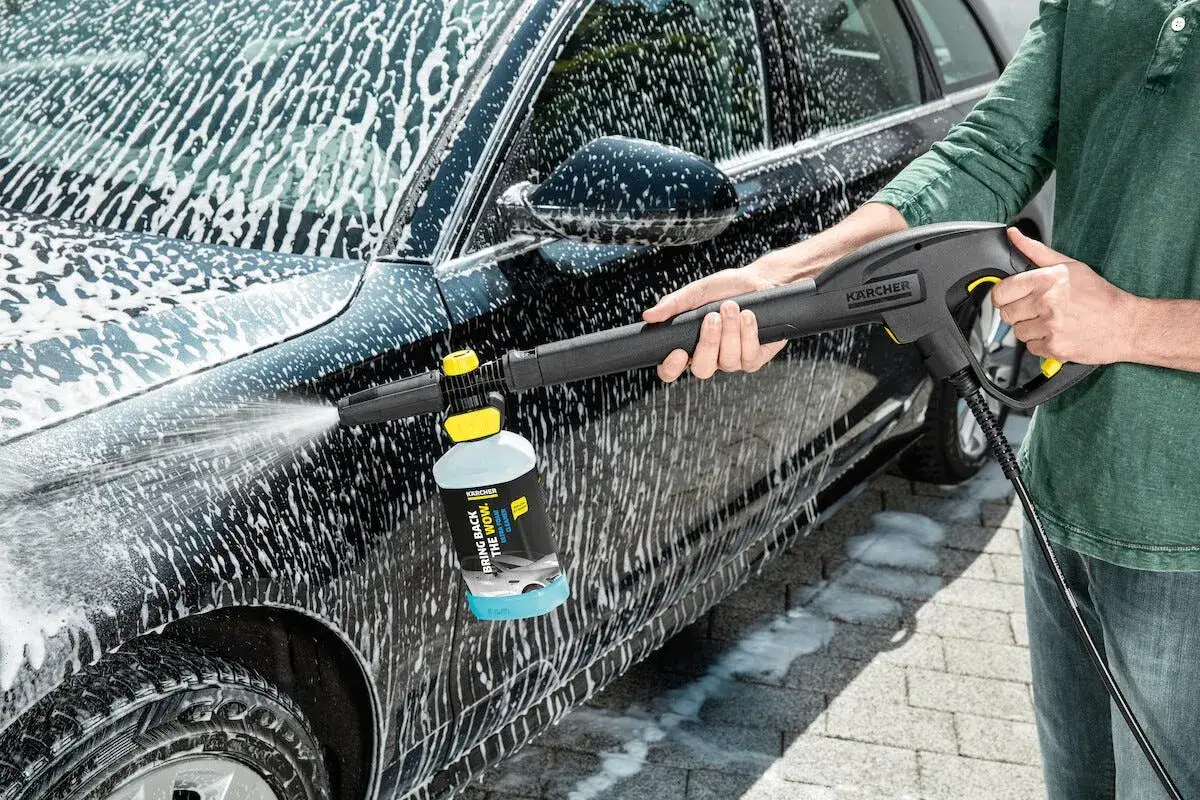 Person tvättar bilen med Kärcher foam. Ett tjockt lager av skum täcker bilen, redo att sköljas av.