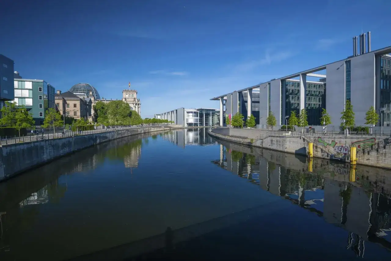 Moderne Geb&auml;ude und der Reichstag spiegeln sich im Wasser. Perfekte ausflugsziele berlin am wasser f&uuml;r einen sonnigen Tag.