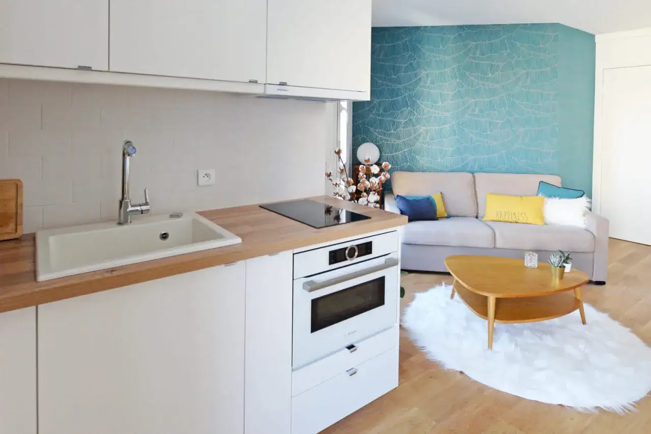 Am&eacute;nagement petite cuisine moderne avec &eacute;vier, plaque induction, four et salon cosy.