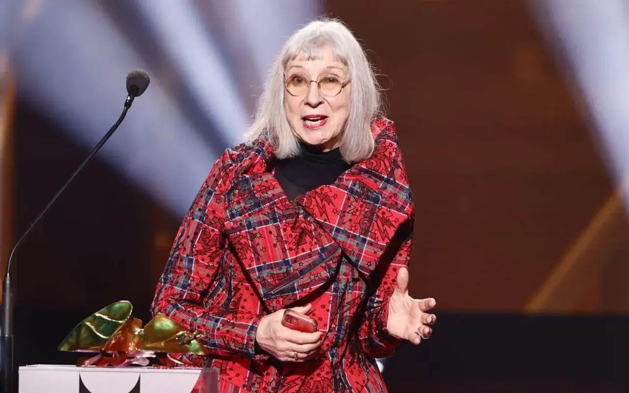 Sofia Kappel talar vid ett podium, kl&auml;dd i en r&ouml;d rutig jacka.