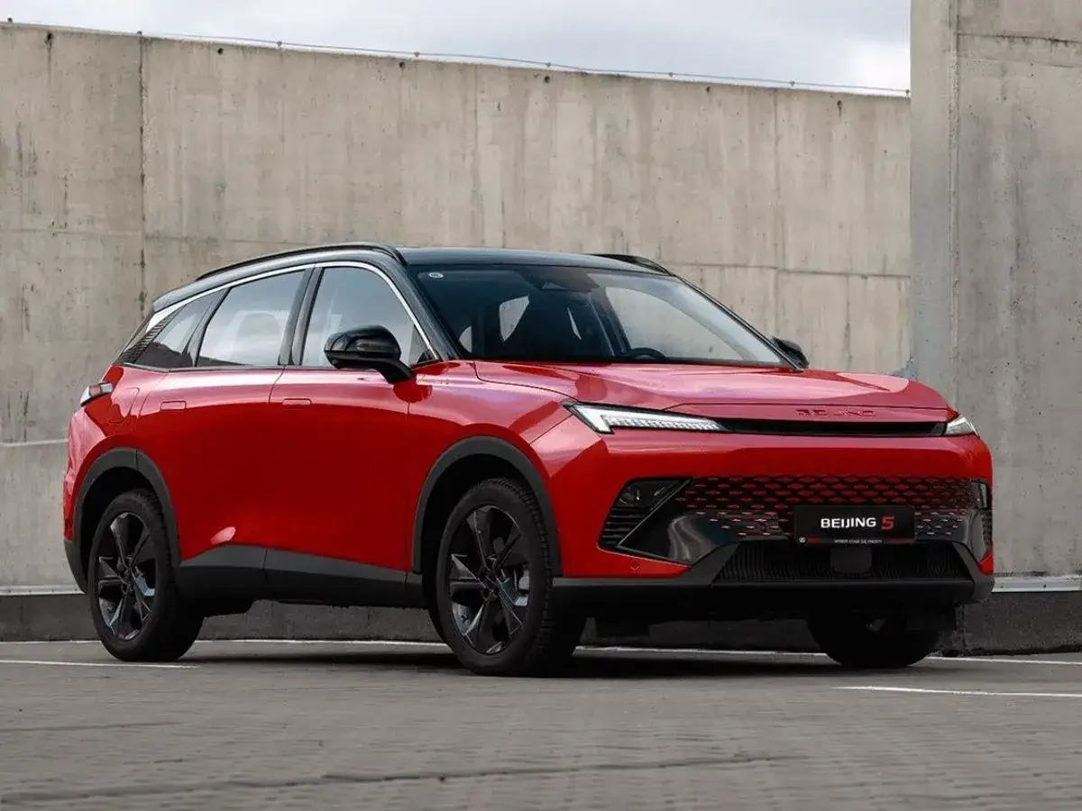 Czerwony SUV BEIJING 5 z czarnym dachem i felgami, zaparkowany przy betonowej ścianie.