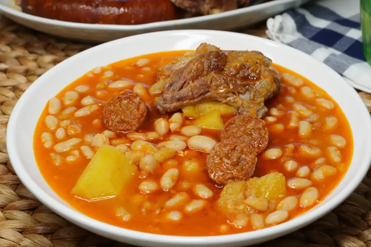 Un plato humeante de alubias con chorizo, patatas y un trozo de carne. Un fest&iacute;n casero listo para disfrutar.