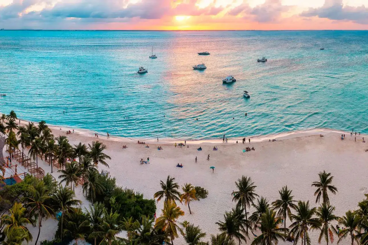 Zachód słońca nad turkusowym morzem w Cancun. Plaże, palmy i łodzie tworzą idealny obraz tego, co zobaczyć w Cancun.