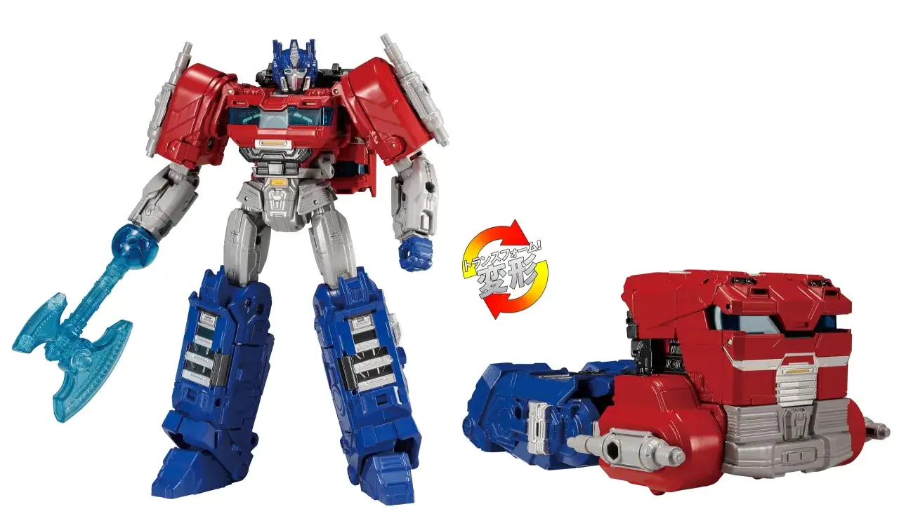 Figurka **Optimus Prime** z Transformers, gotowa do walki z niebieskim toporem. Obok widoczna część transformacji.