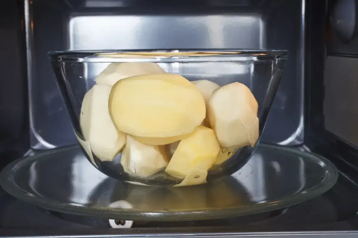 Patate sbucciate in una ciotola di vetro pronte per essere cotte al microonde in 3 minuti.