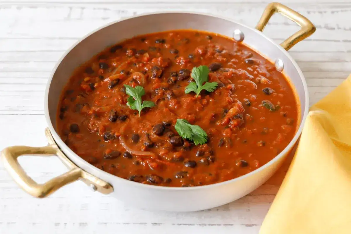 Un saporito piatto di fagioli alla messicana, con fagioli neri in una ricca salsa rossa, guarnito con coriandolo fresco.