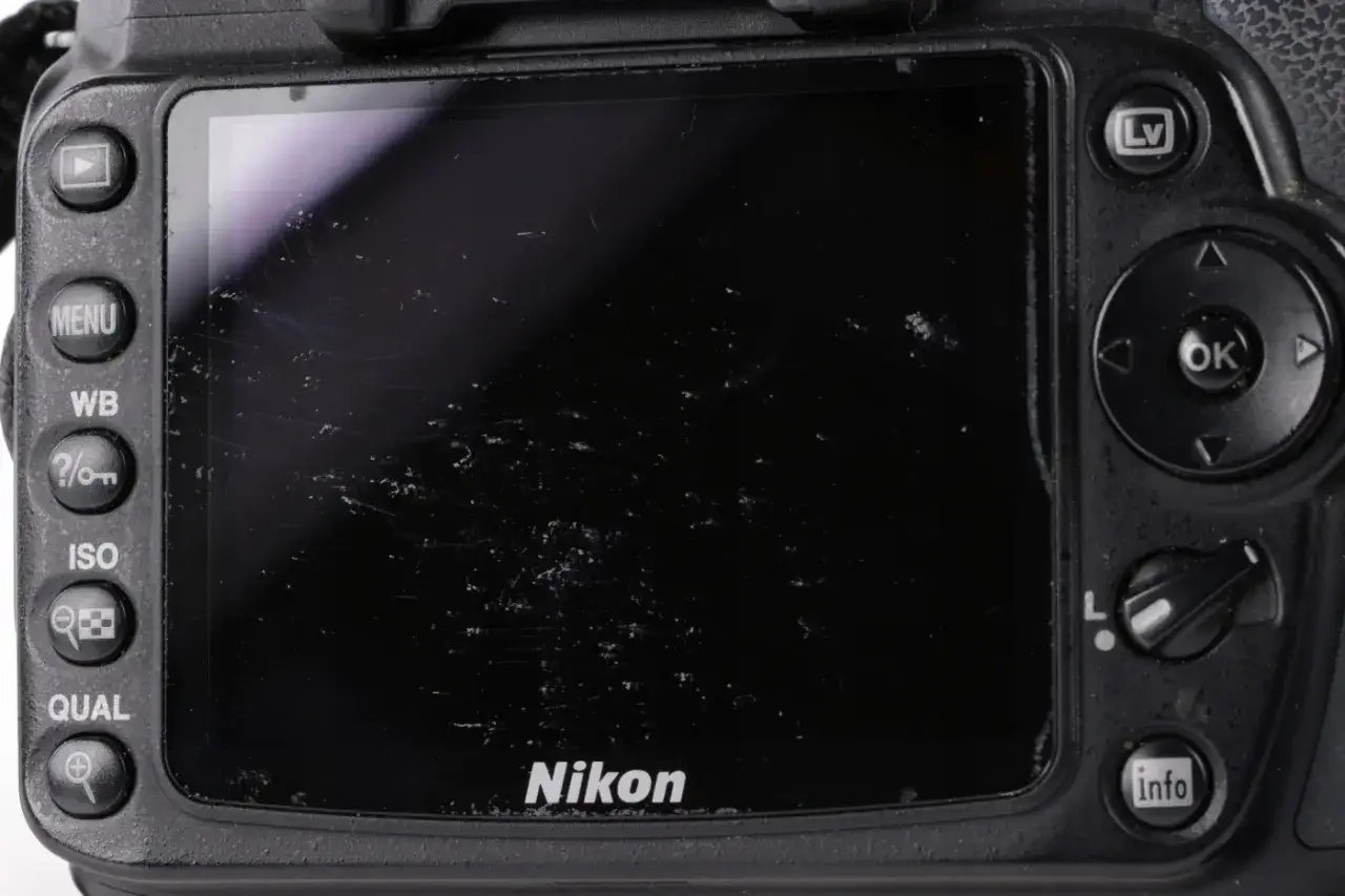 Zarysowany ekran aparatu Nikon D90. Widoczne przyciski MENU, WB, ISO, QUAL. Dane techniczne tego modelu są wciąż poszukiwane.