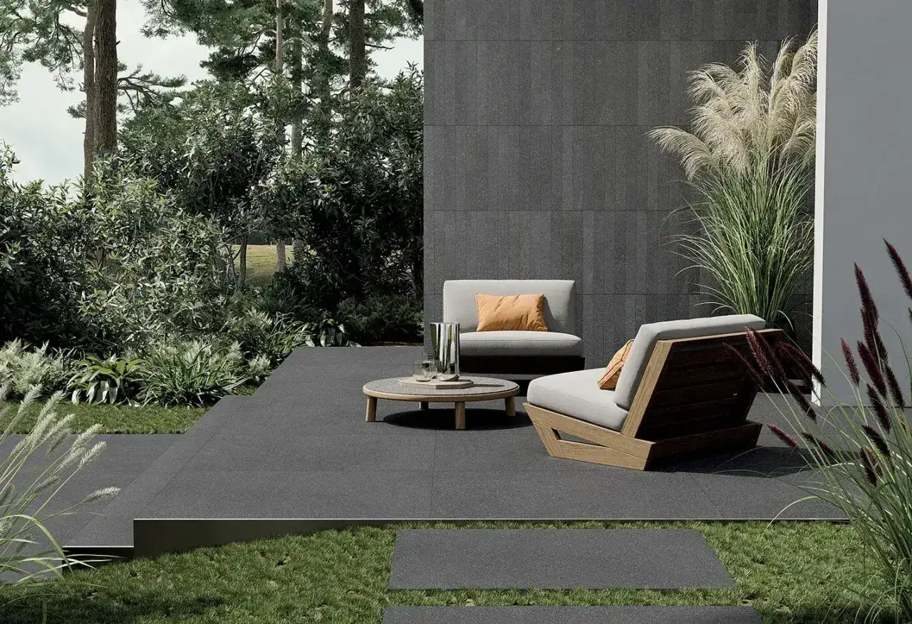Terrazza moderna con mobili da esterno e piastrelle pietra lavica che creano un'atmosfera elegante e naturale.