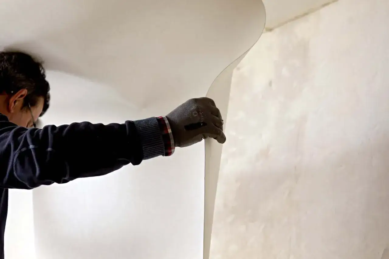 Un homme pose une toile de verre au plafond.