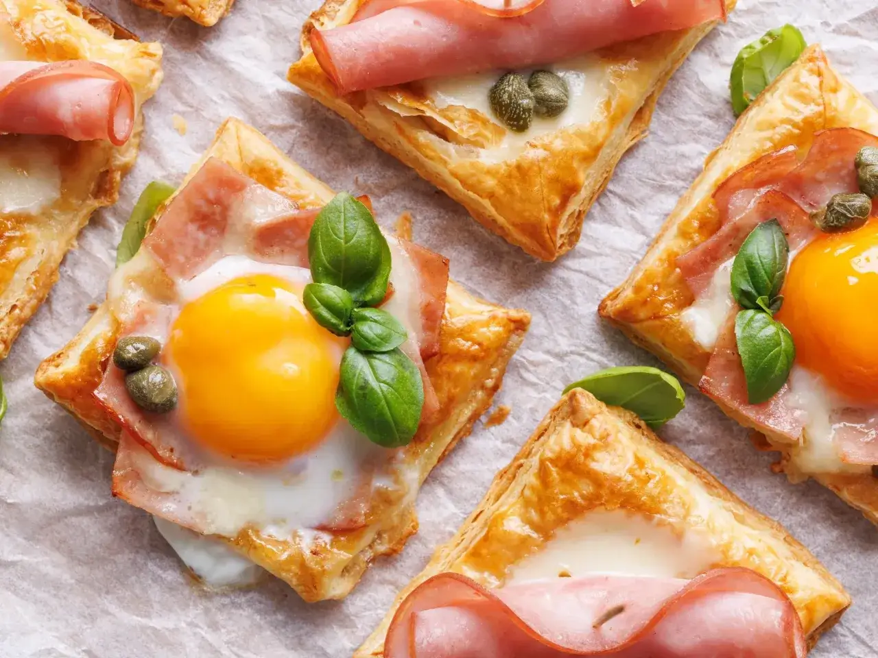 Pyszne tartaletki z ciasta francuskiego z jajkiem, szynką i kaparami. Idealne, gdy zastanawiasz się, w jakiej temperaturze pieczemy ciasto francuskie.