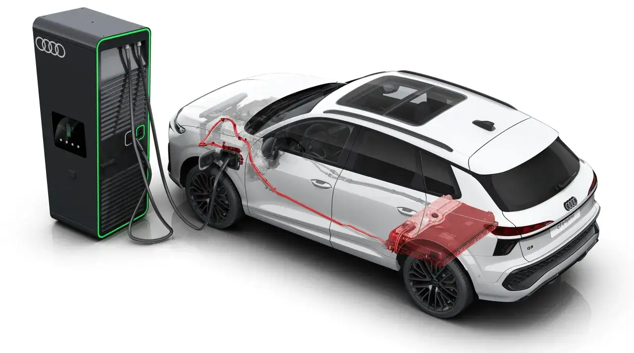 Audi Q3 e-hybrid podłączone do ładowarki. Widoczny schemat układu napędowego z czerwonymi przewodami i baterią.