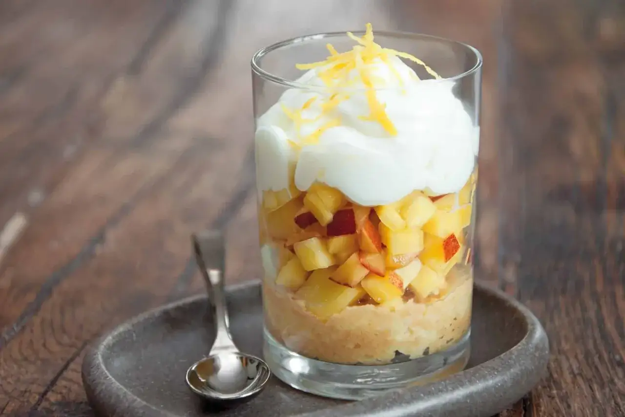 Un d&eacute;licieux tiramisu nectarine, superpos&eacute; dans un verre, avec des fruits frais et une touche de zeste d'agrume.