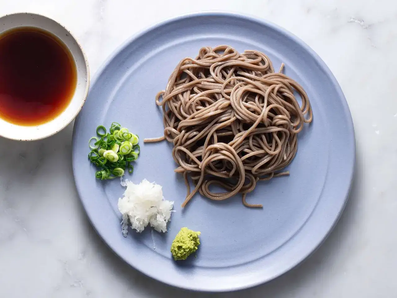 Makaron soba przepis: porcja makaronu z sosem, szczypiorkiem, startą rzodkiewką i wasabi.