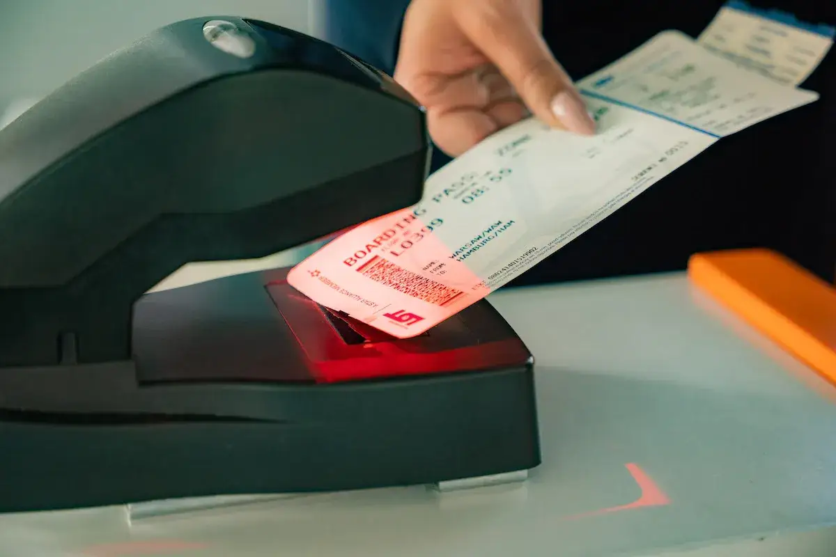 Ręka skanuje kartę pokładową LOT. Może to być etap przed podróżą lub przebukowanie biletu lotniczego.