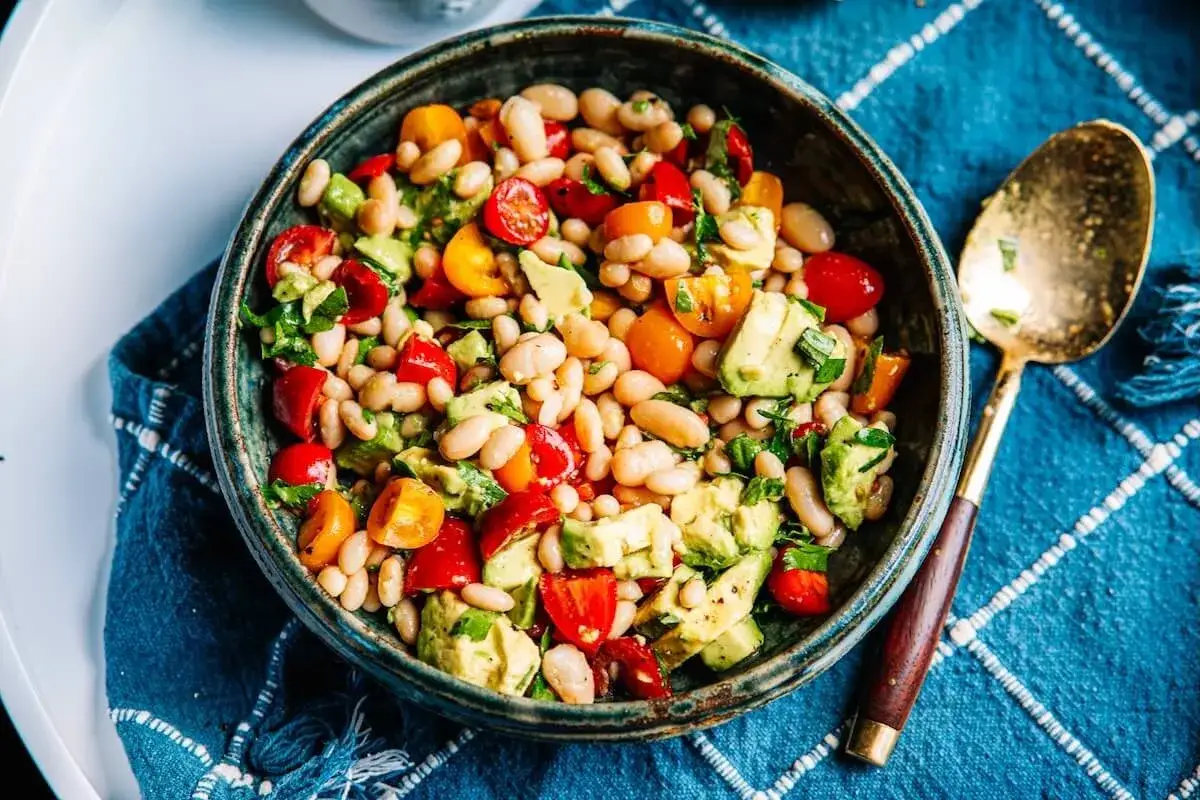 Deliciosa ensalada de alubias blancas con aguacate, tomates cherry y hierbas frescas. Un plato ligero y nutritivo.