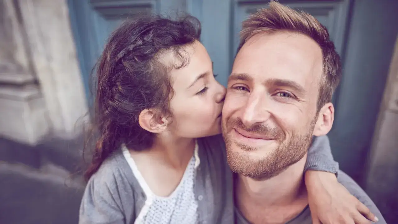Ein kleines M&auml;dchen k&uuml;sst ihren Vater auf die Wange. Eine liebevolle Geste, die an den Vaterkomplex bei Frauen erinnern kann, wenn die Beziehung zu M&auml;nnern von der Vaterfigur gepr&auml;gt ist.