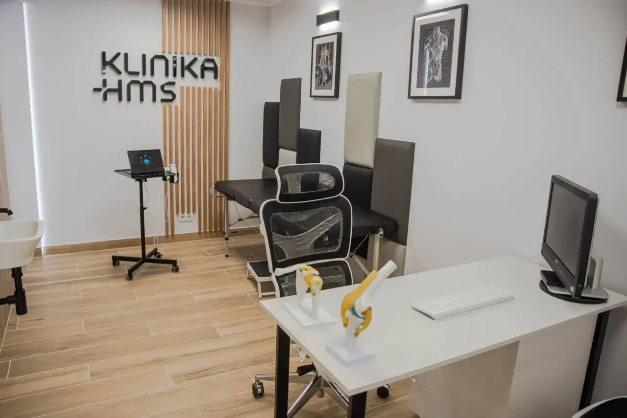 Gabinet ortopedyczny z kozetką, biurkiem, modelem stawu kolanowego i logo