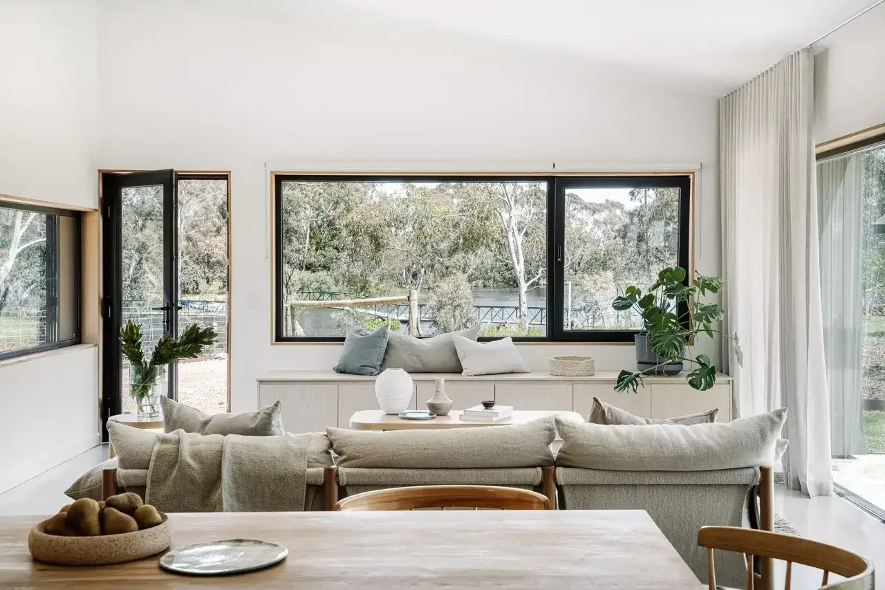 Sal&oacute;n moderno con ventanales grandes para casas que ofrecen vistas al r&iacute;o y la naturaleza.