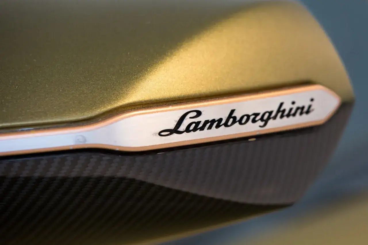 Złote Lamborghini, marka stworzona przez Ferruccio, z logo na karbonowym elemencie.