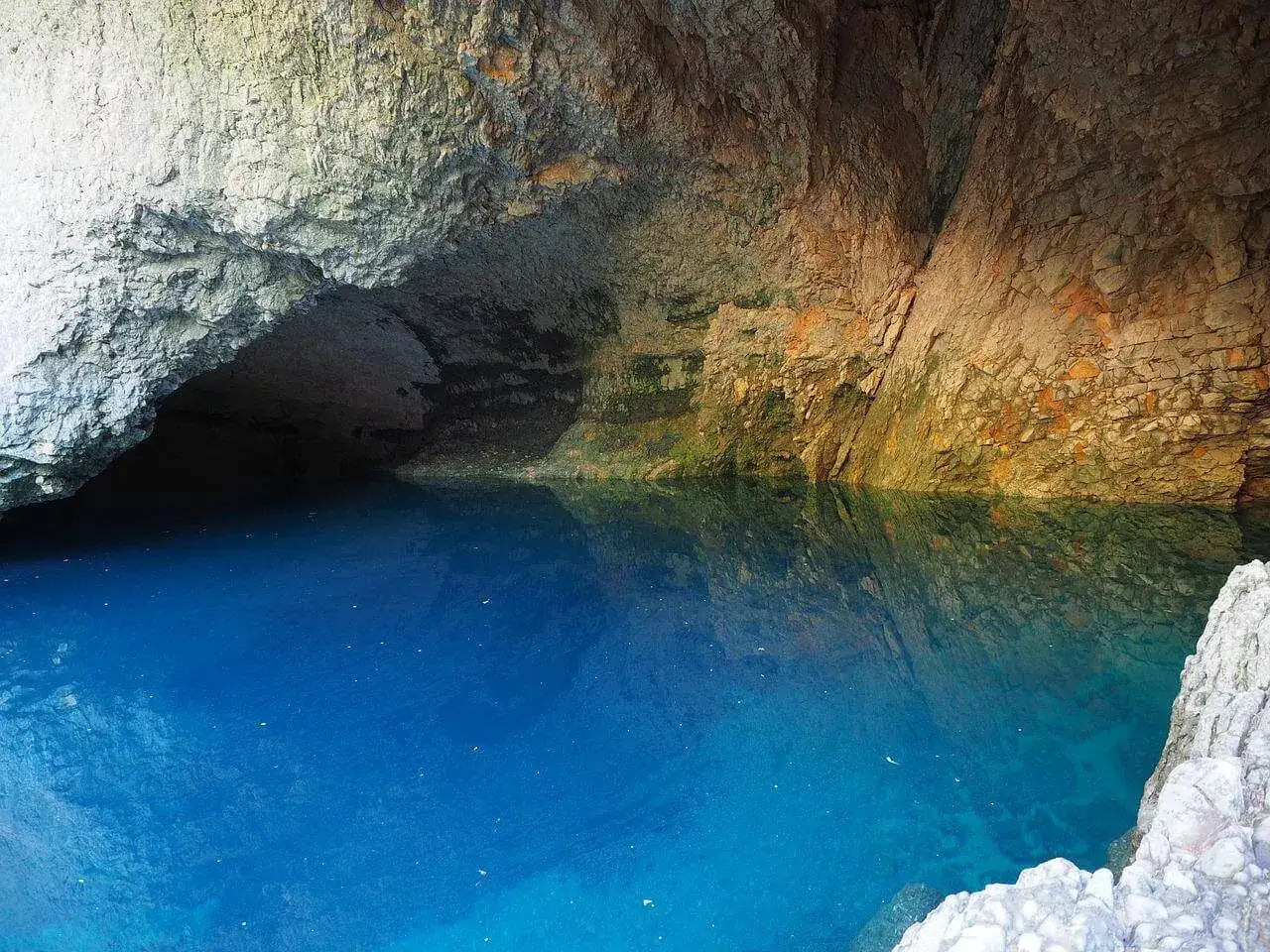 Le gouffre de la Fontaine de Vaucluse, une eau d'un bleu profond émergeant d'une grotte aux parois rocheuses.
