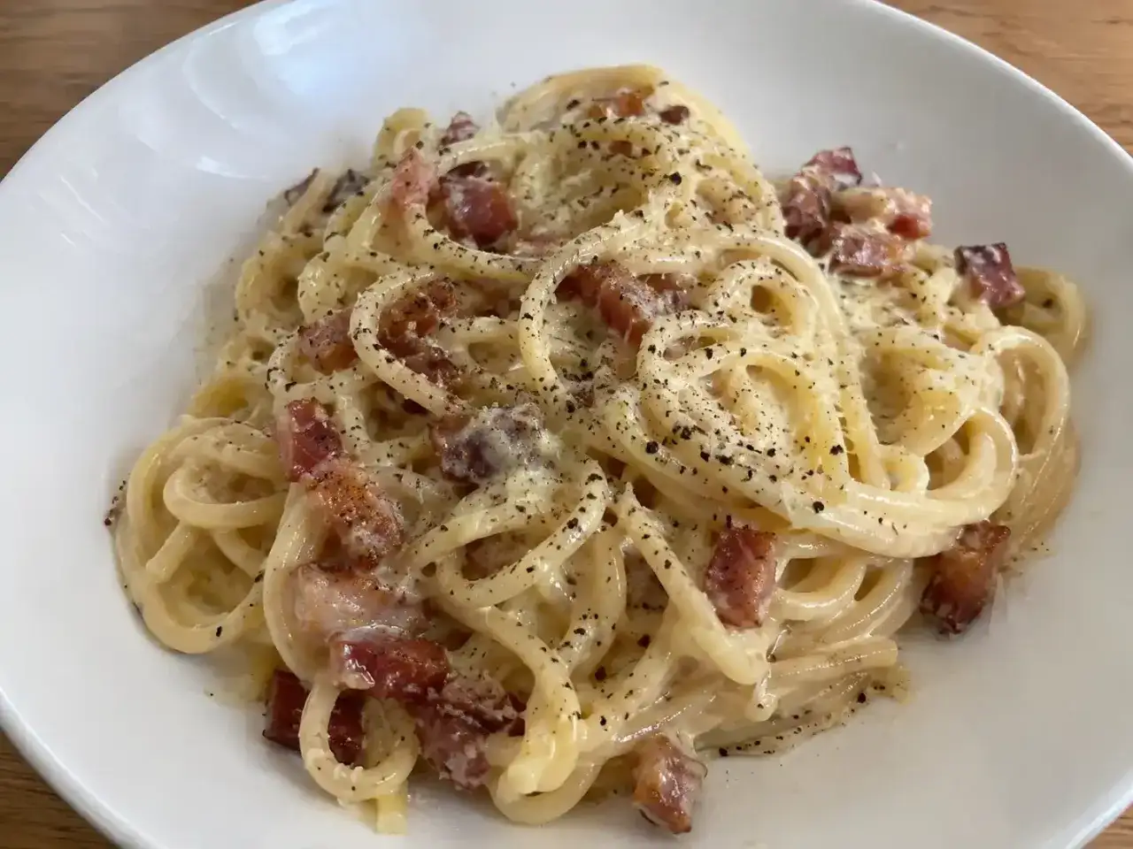 En kr&auml;mig portion pasta carbonara med krispiga bitar av bacon och nymalen svartpeppar.