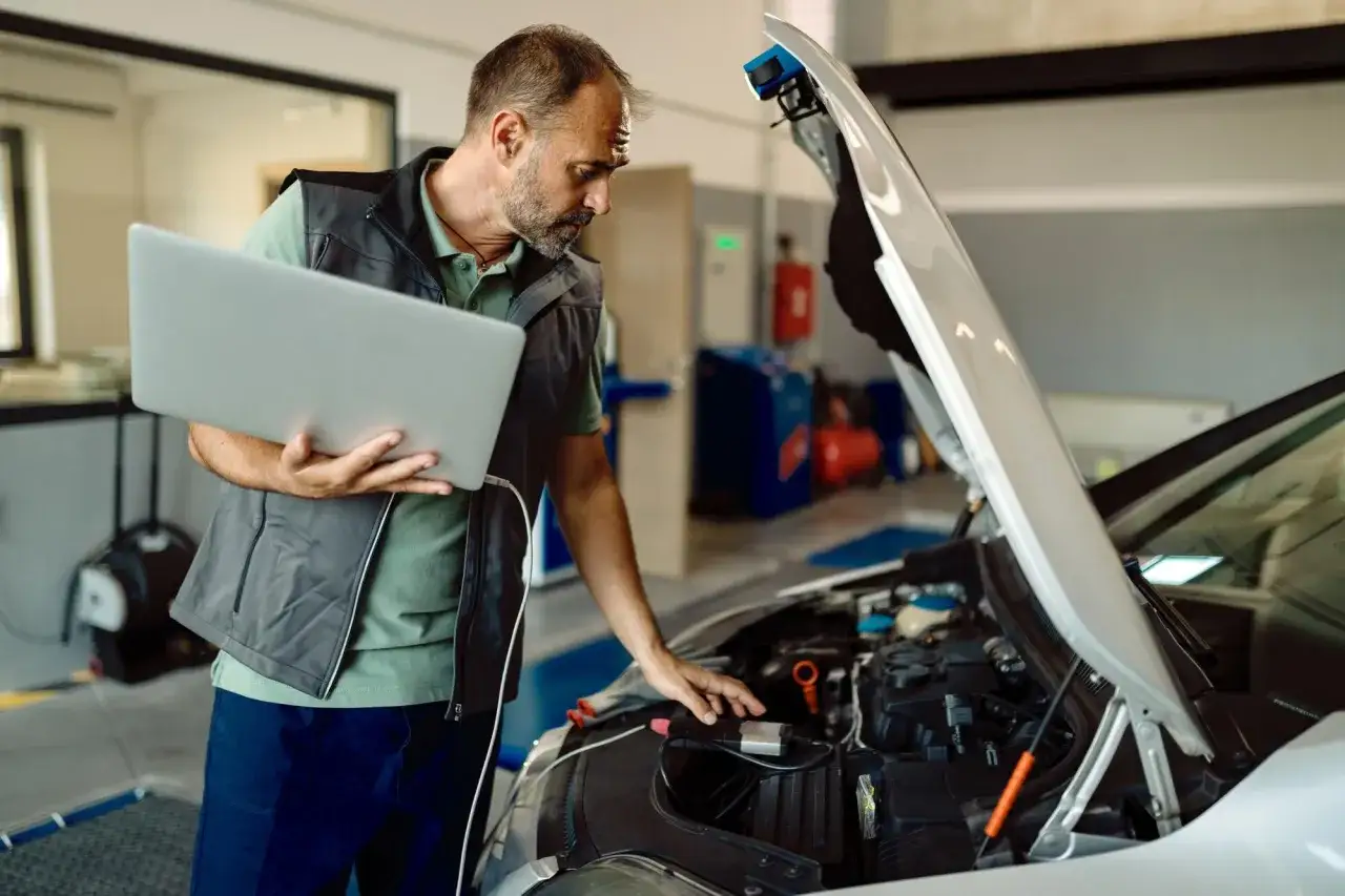 Mechanik podłączający komputer diagnostyczny do samochodu