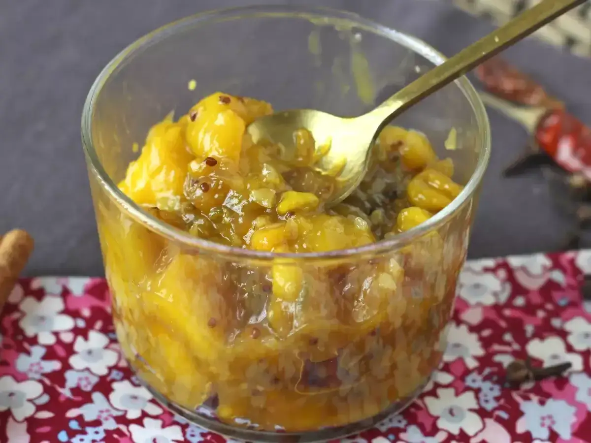 Chutney co to? Słodko-kwaśny sos z owoców, przypraw i octu, idealny do serów i mięs. Złota łyżeczka zanurzona w żółtym, owocowym chutney.