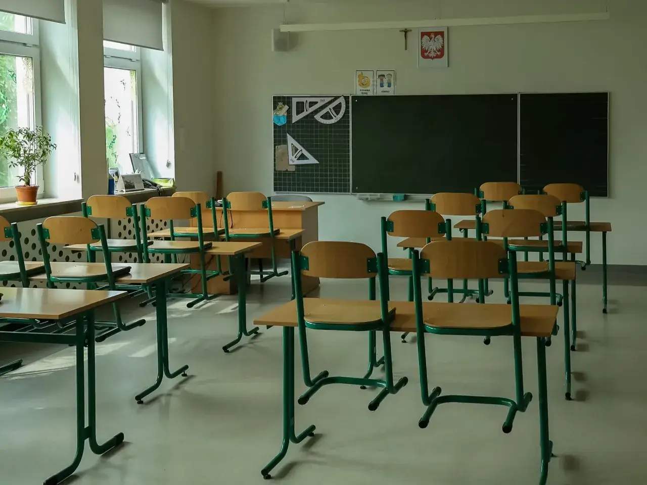 Pusta klasa z rzędami ławek i krzeseł. Na tablicy przybory geometryczne, co sugeruje odwołane zajęcia w szkołach.
