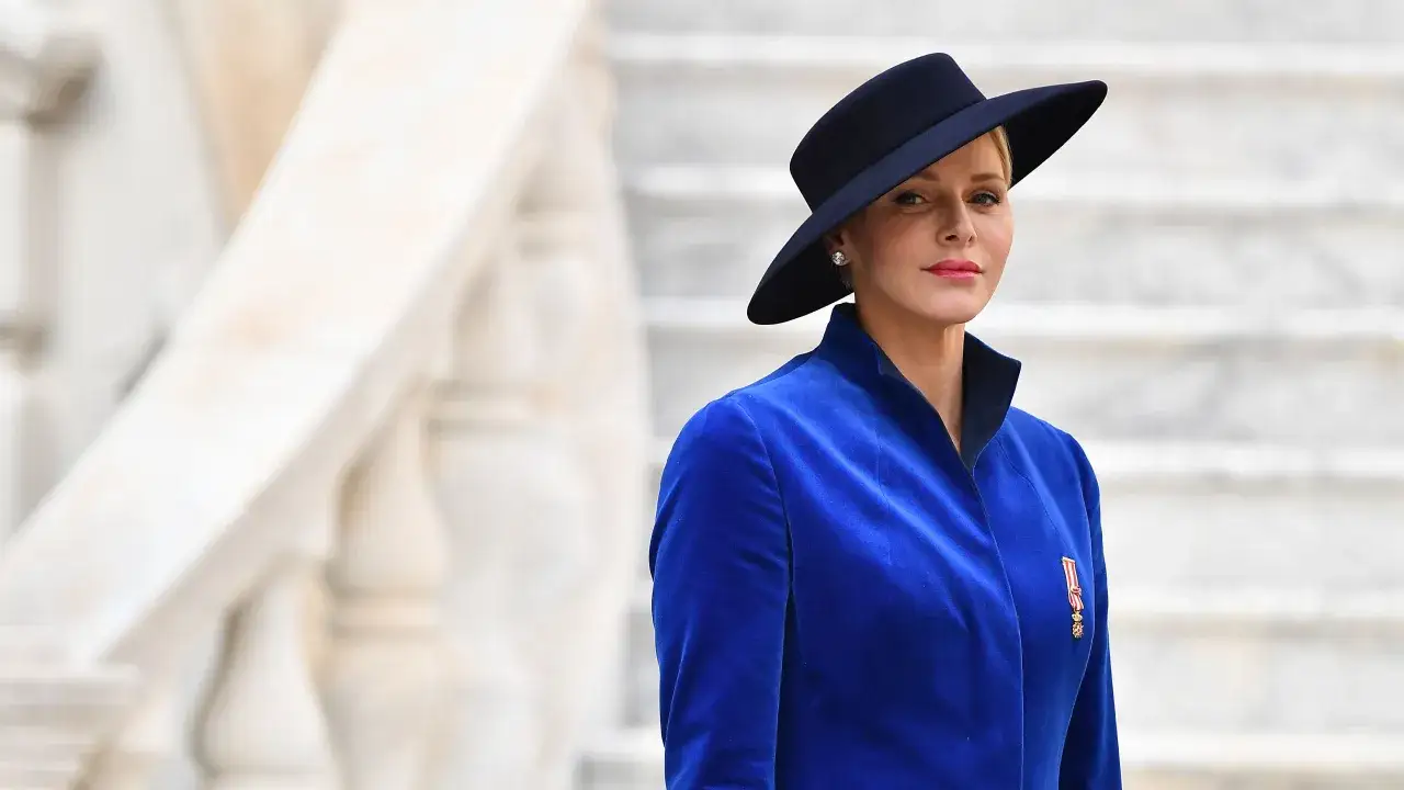 Charlene, furstinna av Monaco, bär en elegant blå sammetsjacka och en mörk hatt.