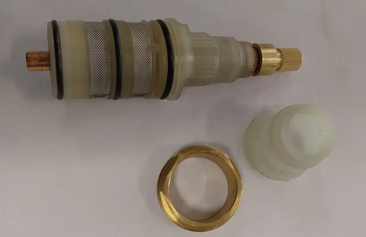Elementy do wymiany głowicy w baterii Omnires: mosiężny pierścień, plastikowa osłona i wkład ceramiczny.