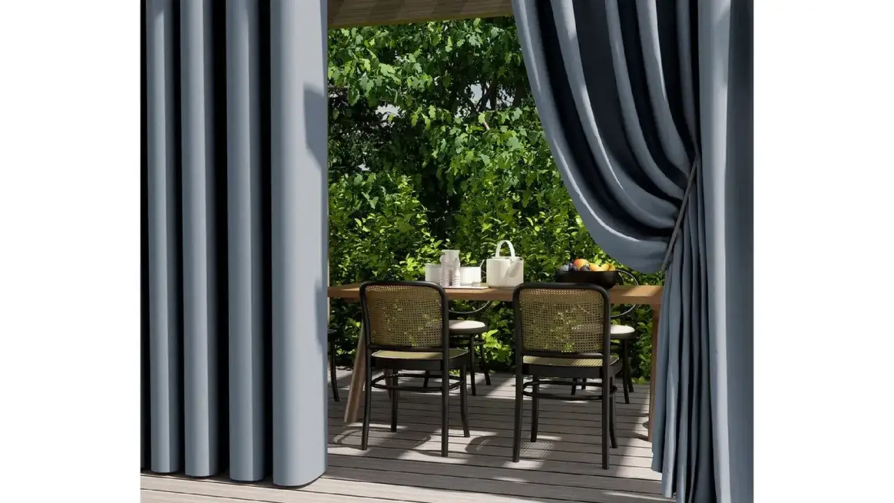 Graue Vorh&auml;nge aus Polyesterstoff rahmen eine Terrasse mit Tisch und St&uuml;hlen ein.