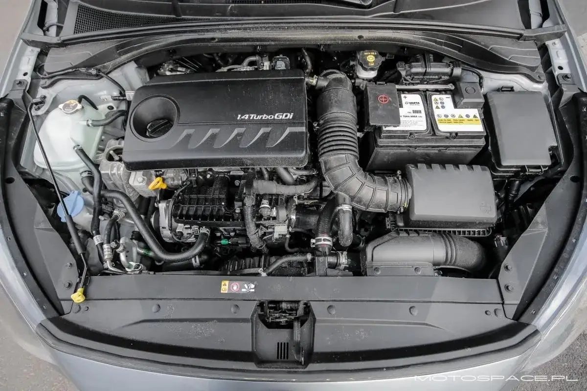 Silnik 1.4 Turbo GDI w Kia Ceed. Widoczny akumulator, układ dolotowy i inne elementy.