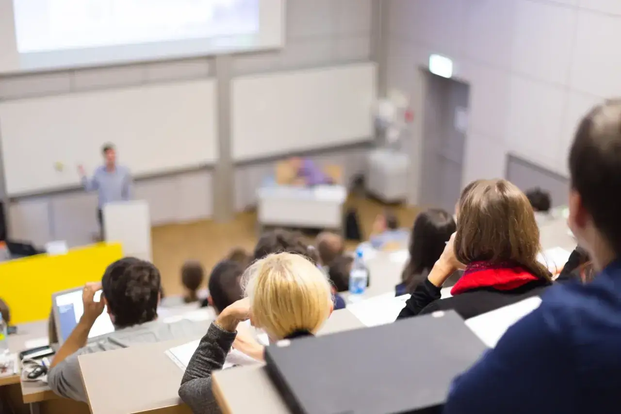 Wykład na uczelni. Studenci słuchają, czy studia stacjonarne są płatne, czy nie.