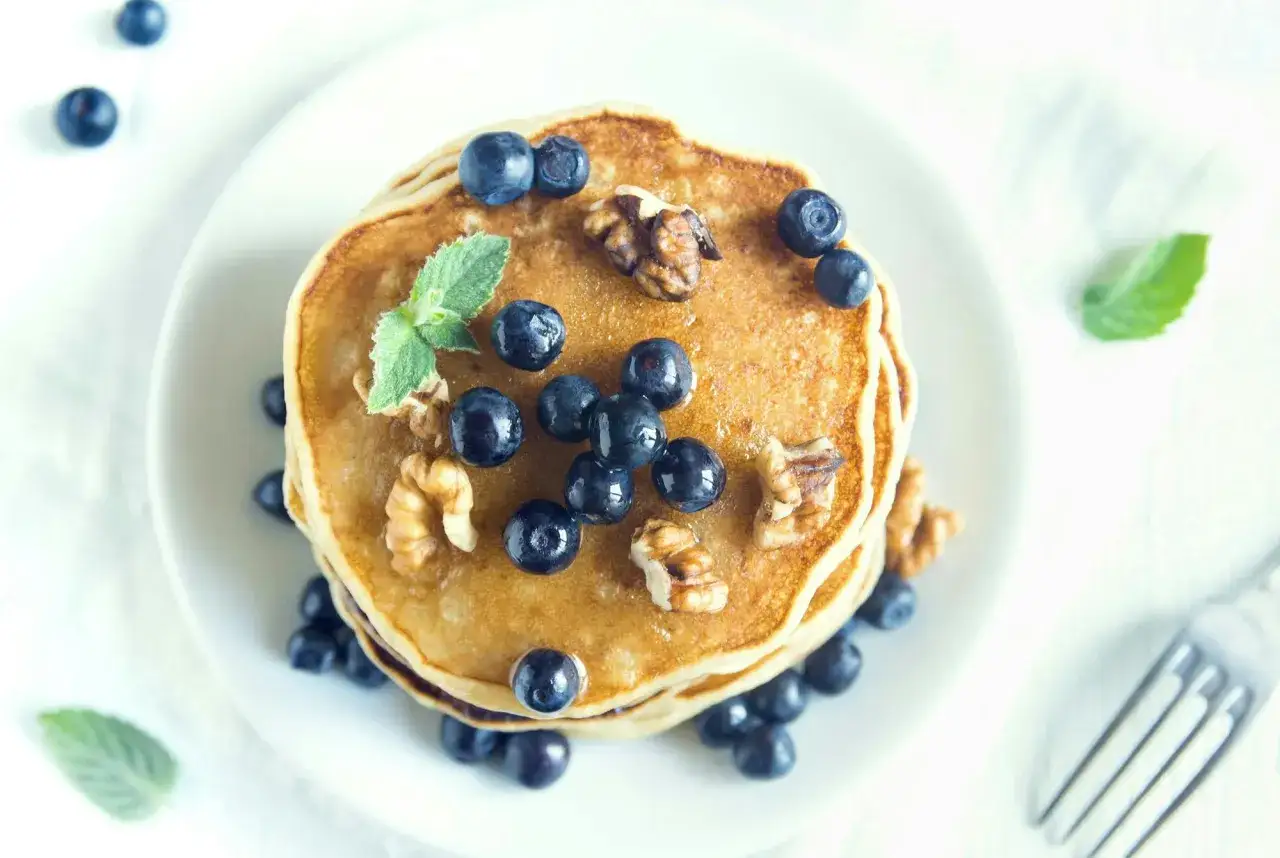 En hög med nyttiga pannkakor toppas med blåbär, valnötter och mynta. En härlig frukost eller mellanmål.